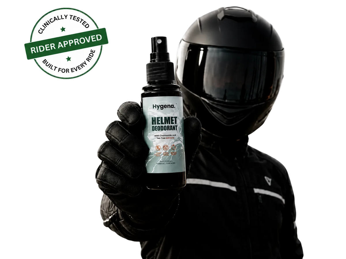 A person in a black motorcycle helmet and gloves holds up a bottle of Hygena Helmet Deodorant.